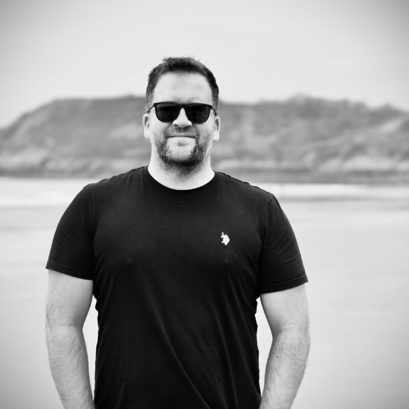 Sam Edwards, founder of Don't Hide, standing on a beach