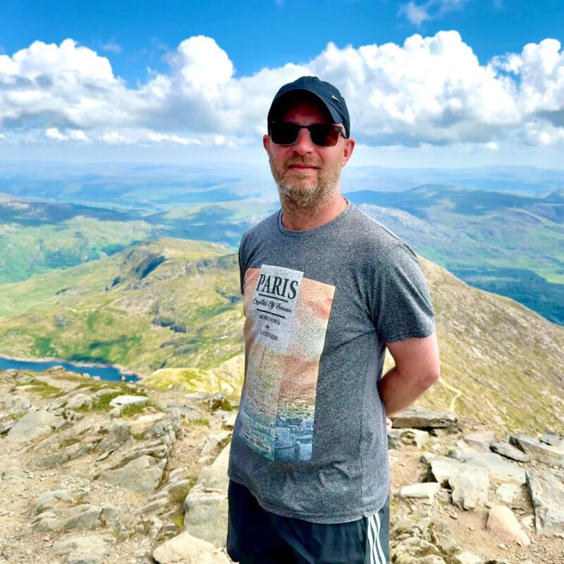 Chris Scott standing on a mountain summit, Don't Hide contributor